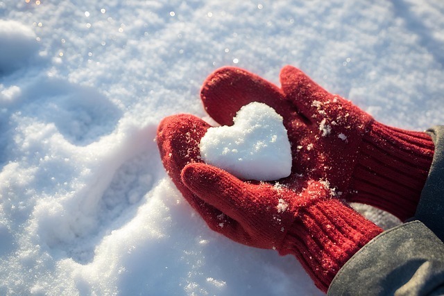 hands holding snow shaped like a heart representing love 